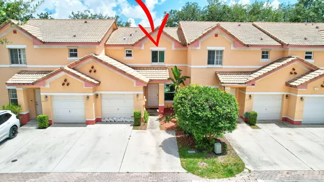 a view of a white house with a yard and potted plants