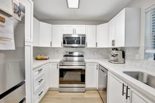 a kitchen with white cabinets appliances and a sink
