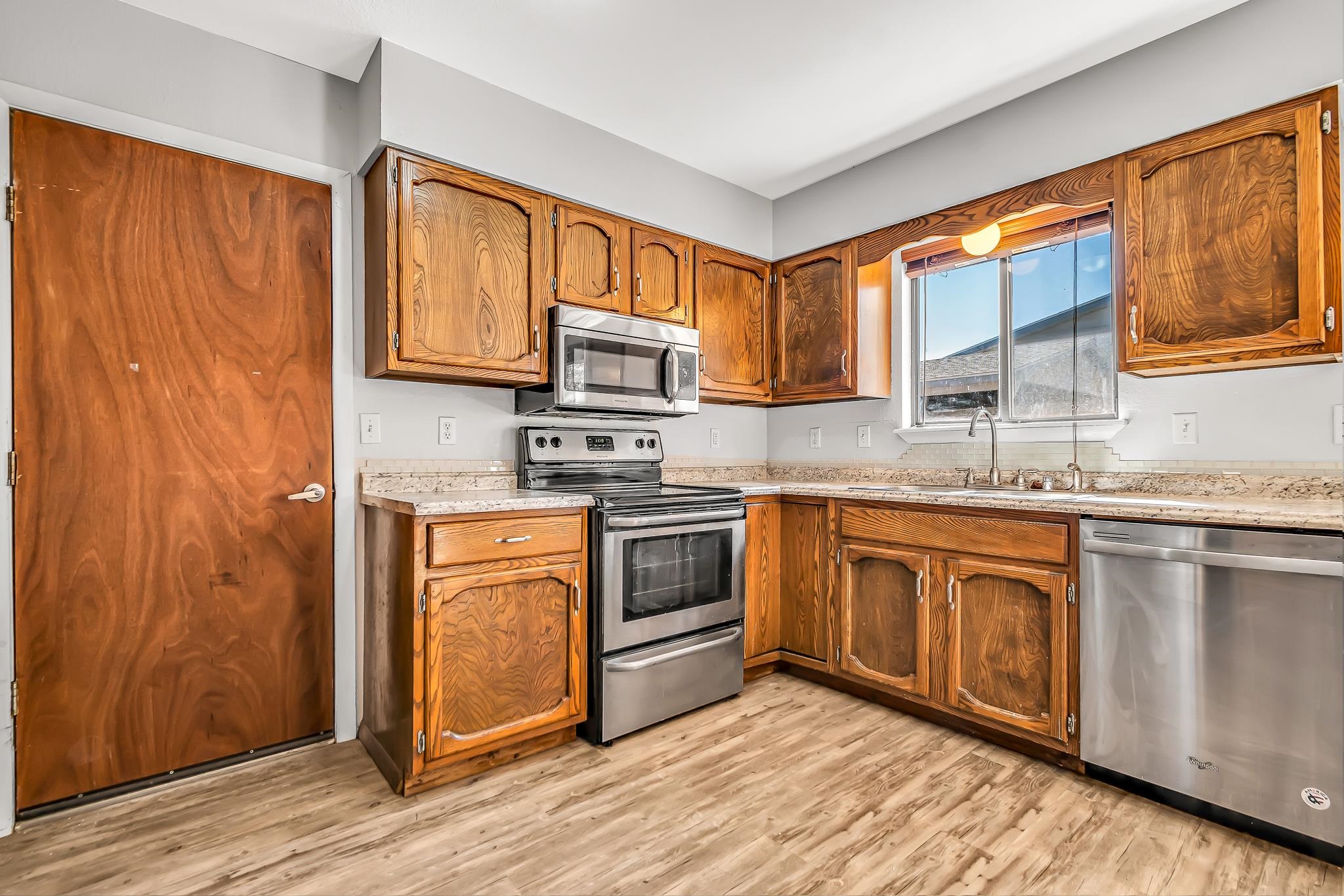 486 Harris Road Grand Junction, CO 81501 - Photo 4 of 15 a kitchen with stainless steel appliances granite countertop a stove a sink dishwasher and a microwave oven with wooden floor