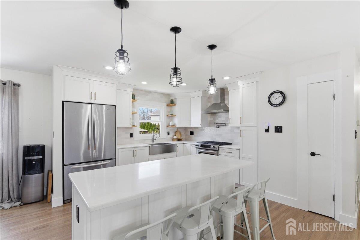 83 Garfield Avenue Colonia, NJ 07067 - Photo 8 of 45 a large kitchen with kitchen island a refrigerator a stove a sink a dining table and chairs