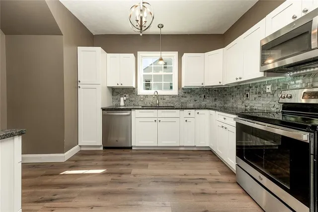 a kitchen with stainless steel appliances granite countertop a stove a sink and a microwave