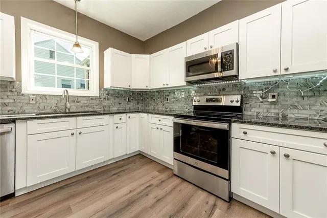 a kitchen with granite countertop white cabinets stainless steel appliances and a sink