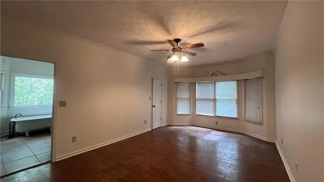 an empty room with chandelier fan and windows