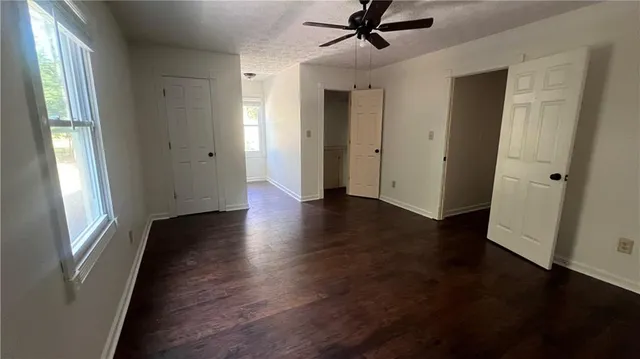 a view of a hallway with wooden floor and a chandelier fan