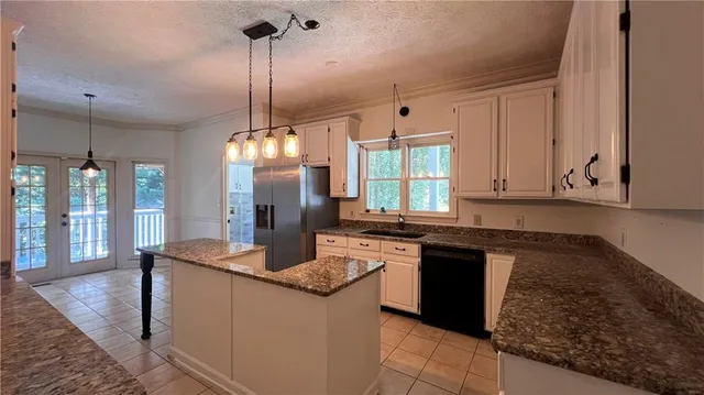 a kitchen with kitchen island granite countertop a sink a counter top space appliances and cabinets
