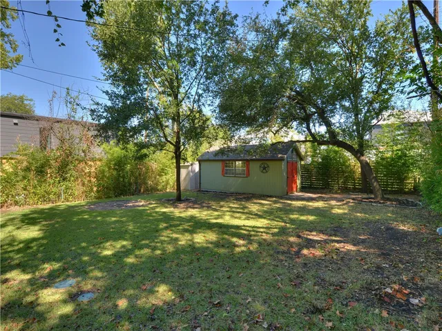 a view of a yard with plants and large trees