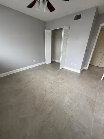 a view of an empty room and chandelier fan