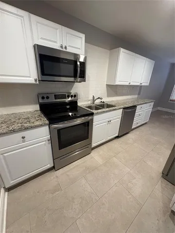 a kitchen with granite countertop a stove top oven microwave and cabinets