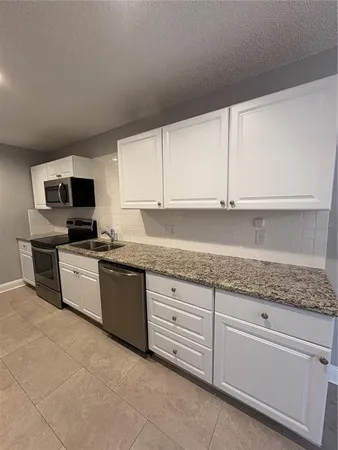 a kitchen with granite countertop white cabinets and stainless steel appliances
