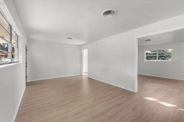 a view of an empty room with a window and wooden floor