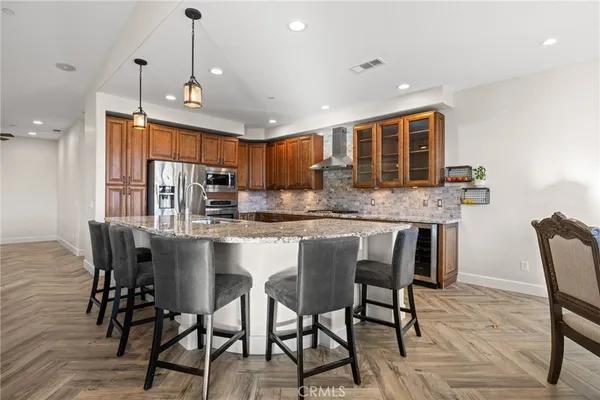 a kitchen with stainless steel appliances kitchen island granite countertop a table chairs sink and cabinets