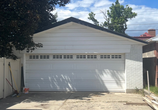 541 Mingo View Avenue Sandy, UT 84070 - Photo 14 of 16 White garage featuring a paneled door with upper window inserts, white siding, white painted brick accents, and a dark shingled roof