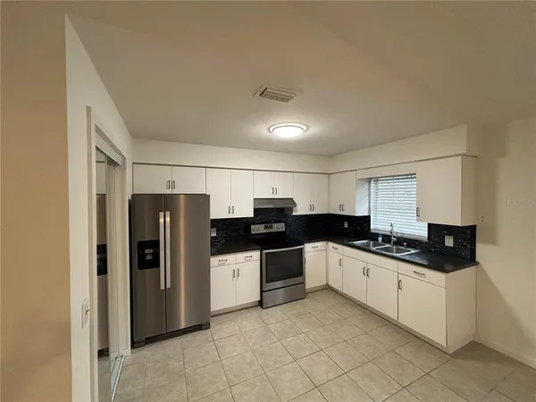 a kitchen with granite countertop a refrigerator and a sink