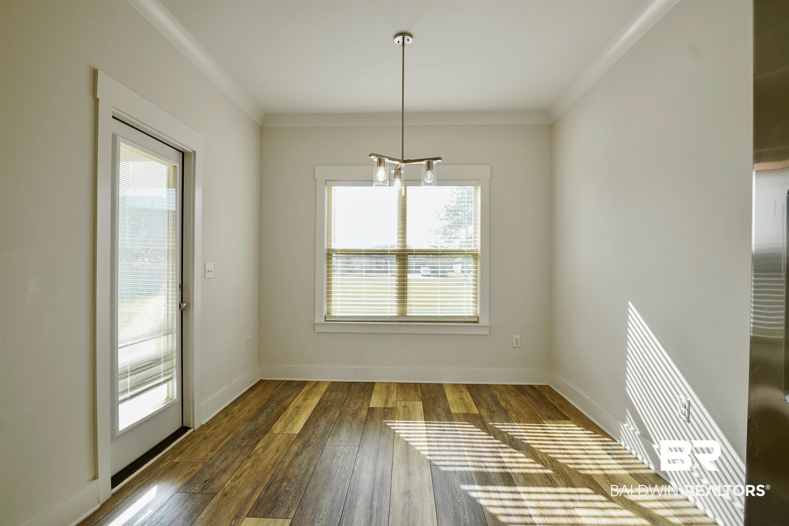 7090 Rocky Rd Loop Gulf Shores, AL 36542 - Photo 12 of 34 Unfurnished dining area with baseboards, wood-type flooring, and crown molding