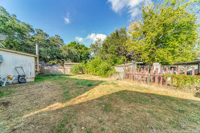 a view of a yard with plants and wooden fence