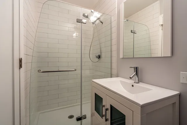 a bathroom with a sink a vanity a shower and a mirror
