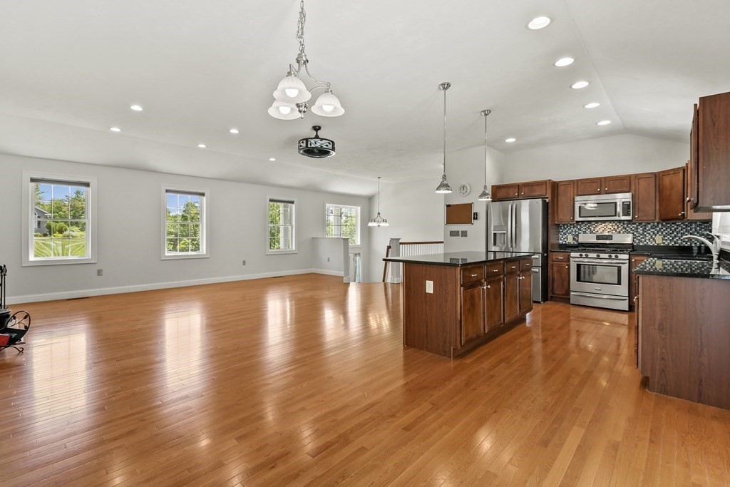 8 Hickory Way Ayer, MA 01432 - Photo 9 of 35 a open kitchen with stainless steel appliances granite countertop a stove top oven and a wooden floors