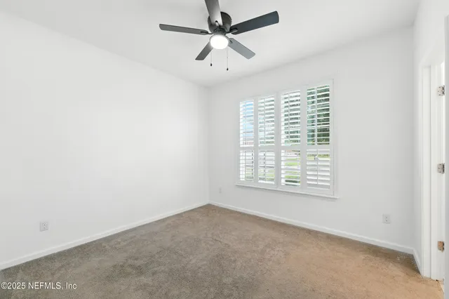 an empty room with a window and a fan