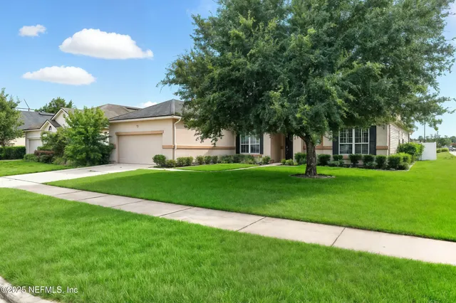 a view of a house with a big yard and large trees