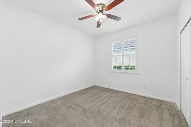 an empty room with a window and a fan