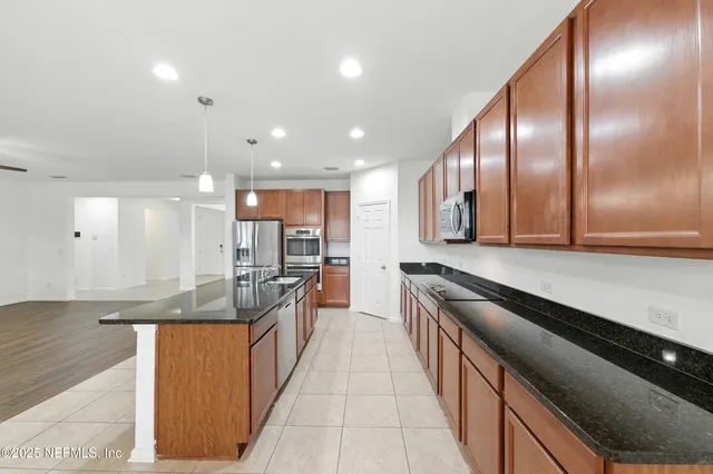 a large kitchen with stainless steel appliances a large counter top a stove and a sink