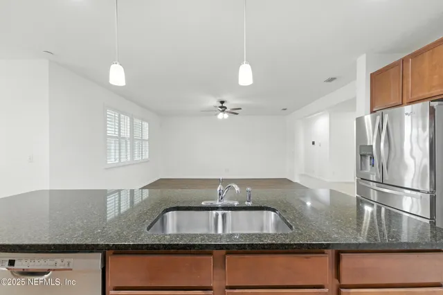 a kitchen with granite countertop a sink a refrigerator and a stove