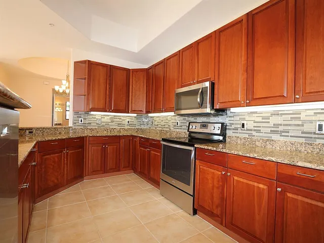 a kitchen with granite countertop wooden cabinets stainless steel appliances and a sink