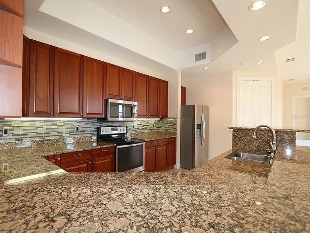 a kitchen with stainless steel appliances granite countertop a refrigerator stove top oven and sink