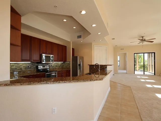 a large kitchen with stainless steel appliances kitchen island granite countertop a large counter top and a stove top oven