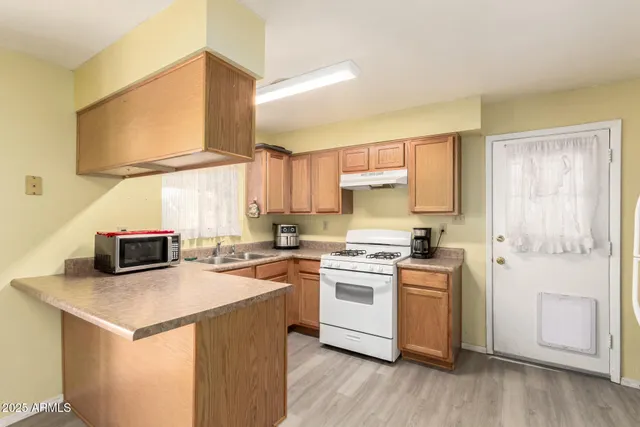 a kitchen with stainless steel appliances granite countertop a stove a sink dishwasher and a refrigerator with wooden floor