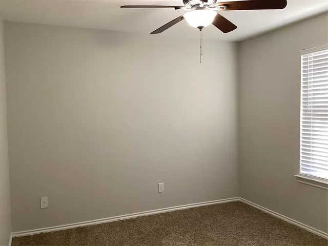 an empty room with a window and a ceiling fan