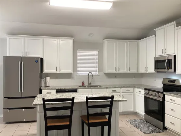 a kitchen with granite countertop a stove top oven cabinets and a refrigerator