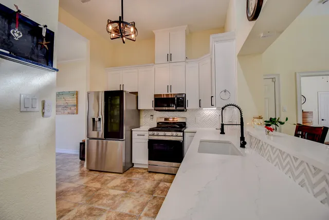 a kitchen with stainless steel appliances granite countertop a refrigerator a stove and a sink