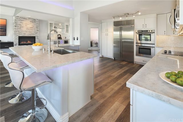 a large kitchen with stainless steel appliances kitchen island granite countertop a table chairs in it and a wooden floors