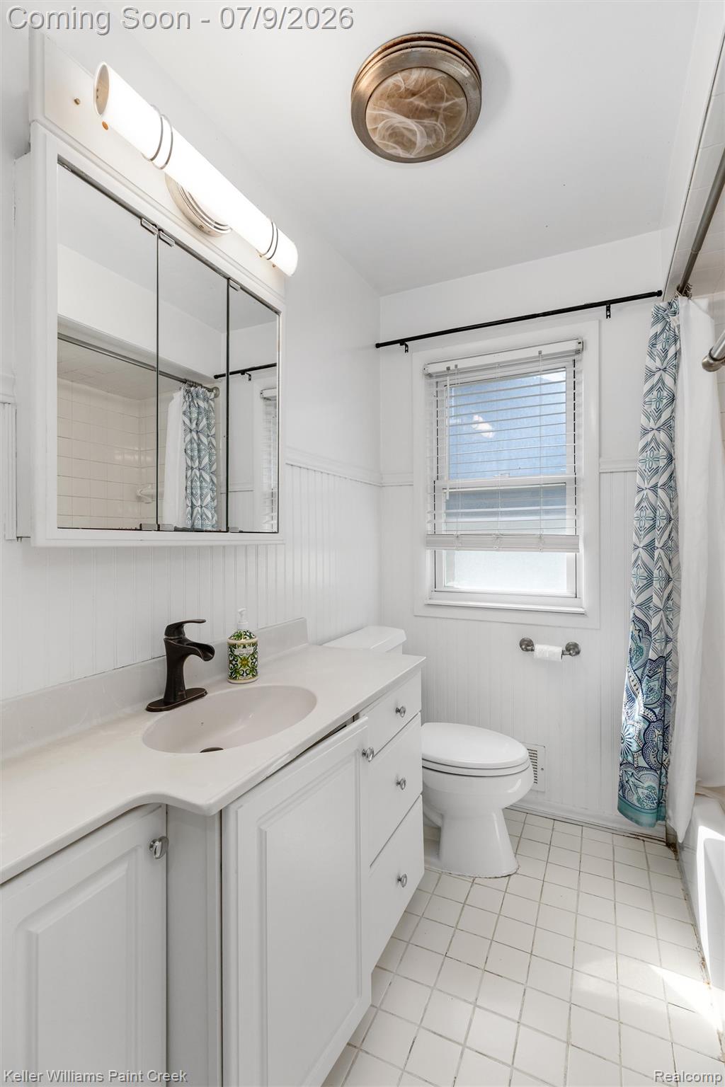 2731 Crooks Road Royal Oak, MI 48073 - Photo 4 of 34 White vanity with an integrated sink and dark bronze faucet, beadboard wainscoting, white window blinds, tiled flooring, and a flush mount ceiling light