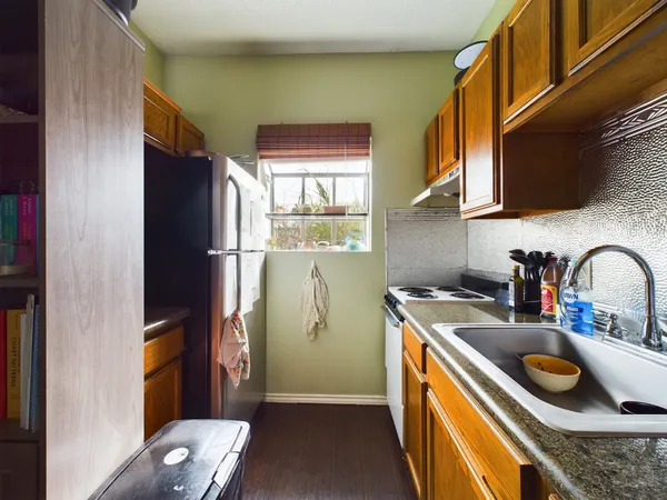 a kitchen with stainless steel appliances granite countertop a refrigerator a sink a stove and a refrigerator