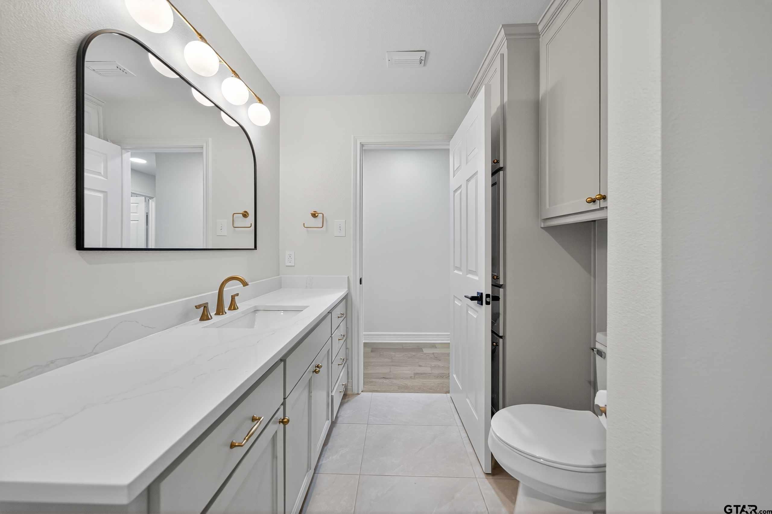 3409 Pebblebrook Drive Tyler, TX 75707 - Photo 37 of 48 a bathroom with a sink a toilet a mirror and vanity