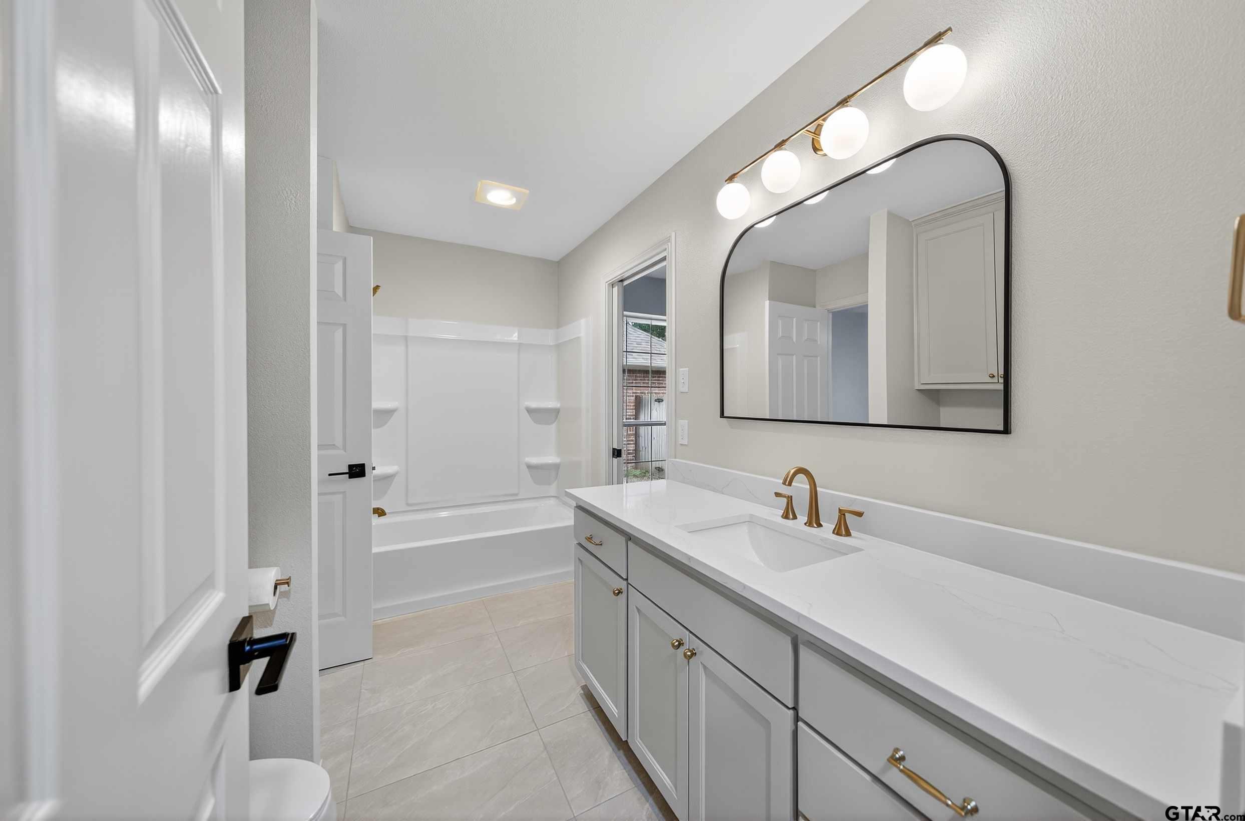 3409 Pebblebrook Drive Tyler, TX 75707 - Photo 38 of 48 a spacious bathroom with a double vanity sink a mirror and a bathtub