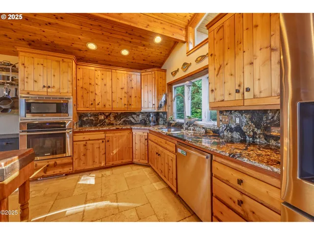a kitchen with stainless steel appliances kitchen island granite countertop a refrigerator and wooden cabinets