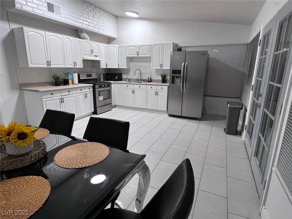 5415 Oxbow Street Las Vegas, NV 89119 - Photo 6 of 20 Kitchen featuring white cabinets, appliances with stainless steel finishes, backsplash, light countertops, and light tile patterned floors