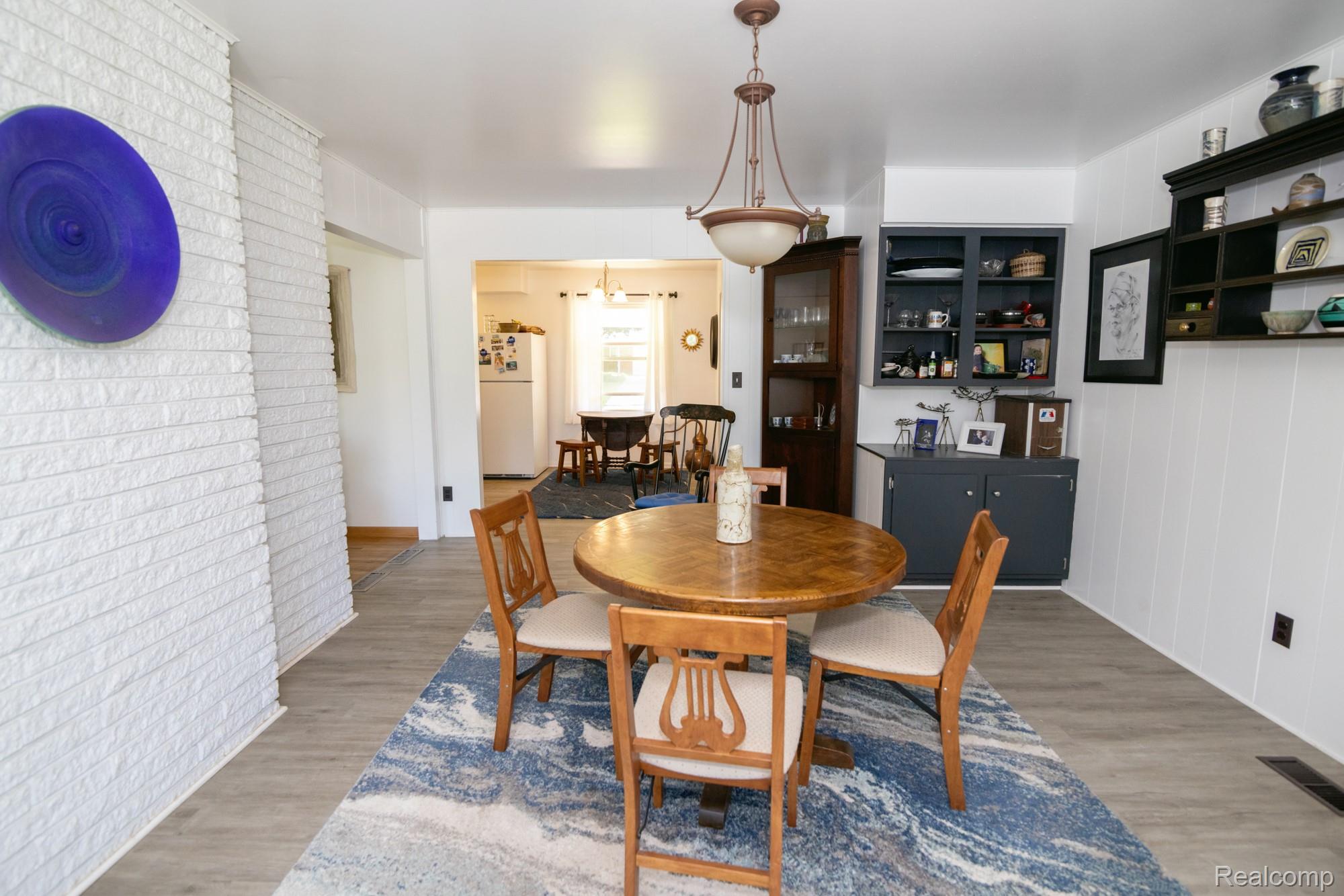 724 Sandstone Drive Rochester, MI 48309 - Photo 25 of 60 Open dining area featuring wood-finish flooring, a white painted brick accent wall, and built-in cabinetry with a dark finish