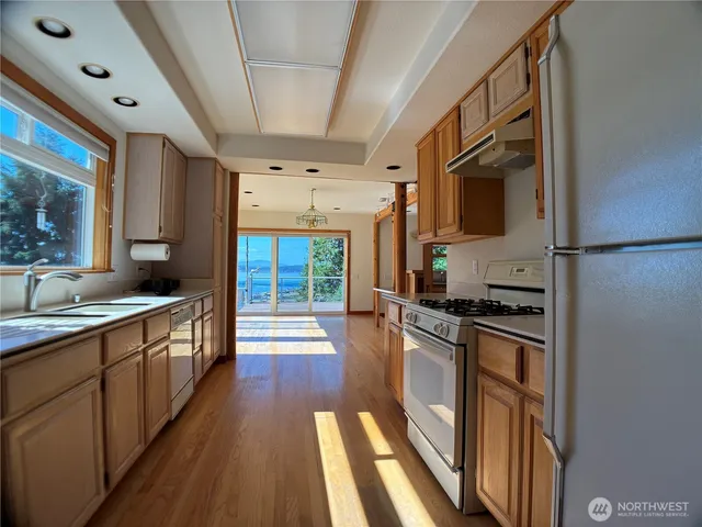 a large kitchen with stainless steel appliances granite countertop a lot of counter space and wooden floors