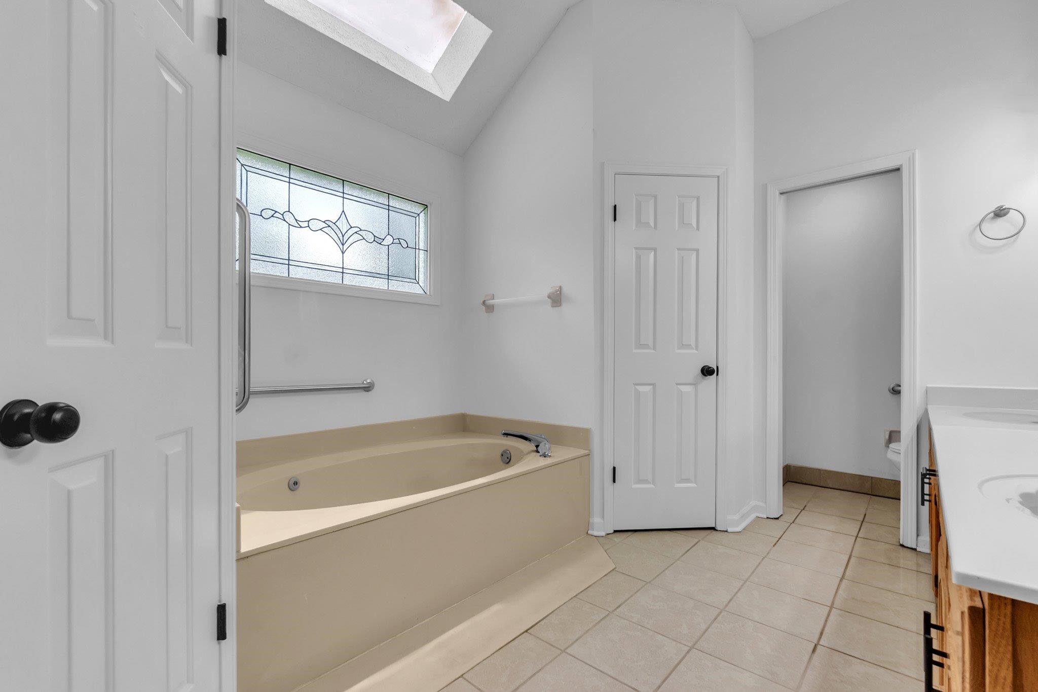 6613 Stephan Ridge Drive Bartlett, TN 38135 - Photo 19 of 24 Bathroom featuring a built-in jetted tub, decorative frosted window, and a skylight