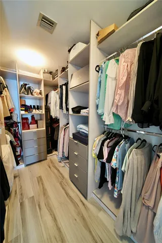 a view of walk in closet with clothes and shoes