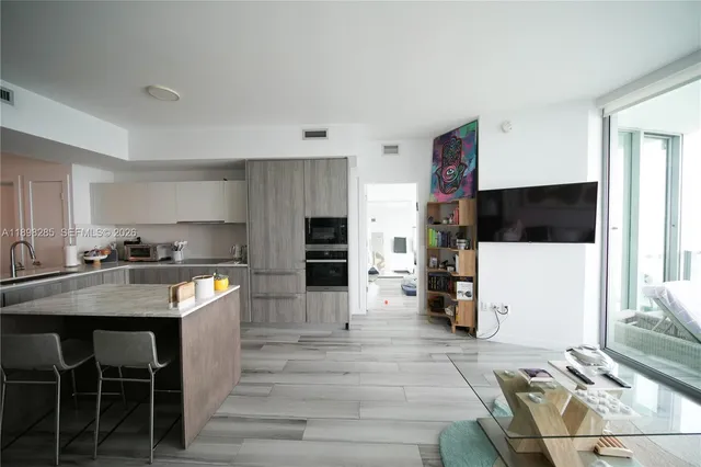 a kitchen with stainless steel appliances kitchen island granite countertop a table chairs sink and cabinets