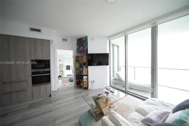 a living room with furniture a flat screen tv and a refrigerator