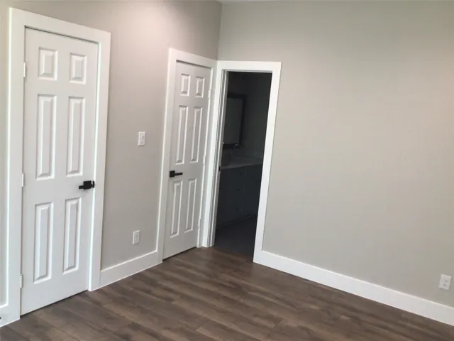 an empty room with wooden floor & closet area