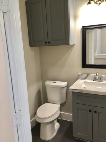 a bathroom with a granite countertop toilet sink and mirror
