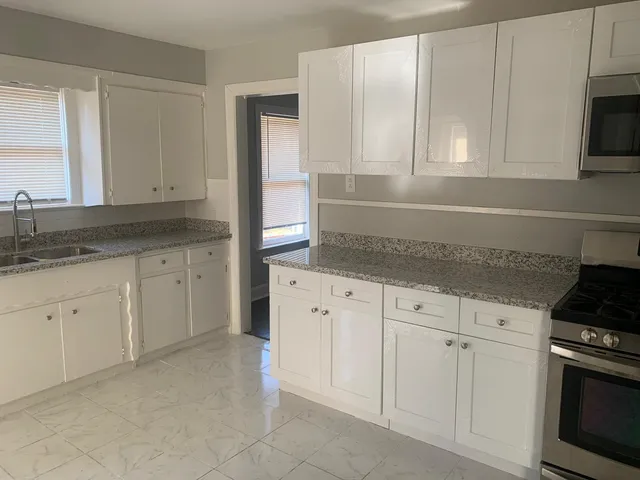 a kitchen with granite countertop white cabinets and stainless steel appliances