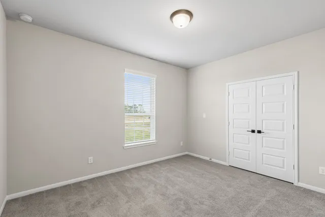 an empty room with windows and closet area